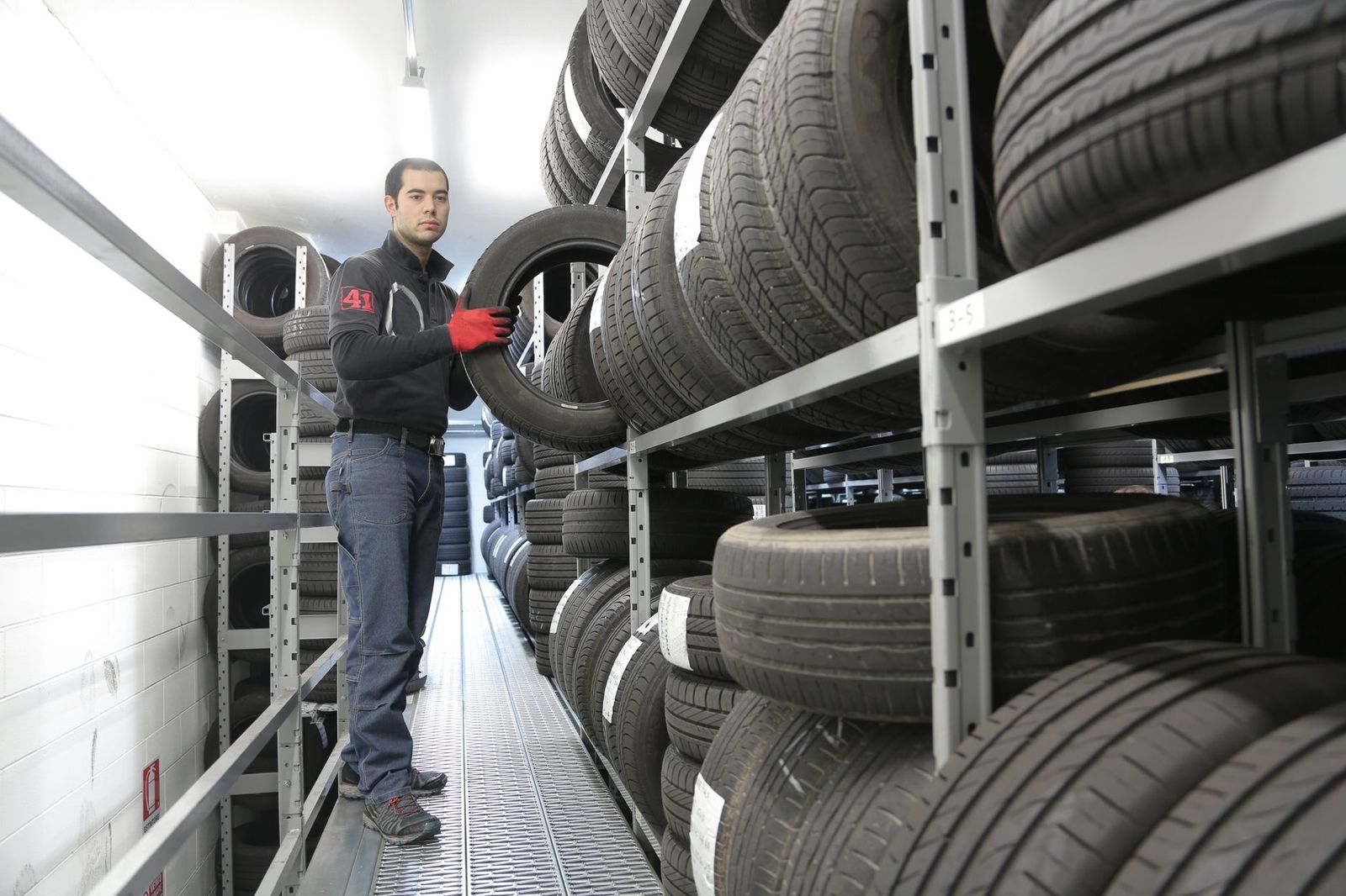 Employé vérifiant des pneus entreposés sur des étagères à l'atelier