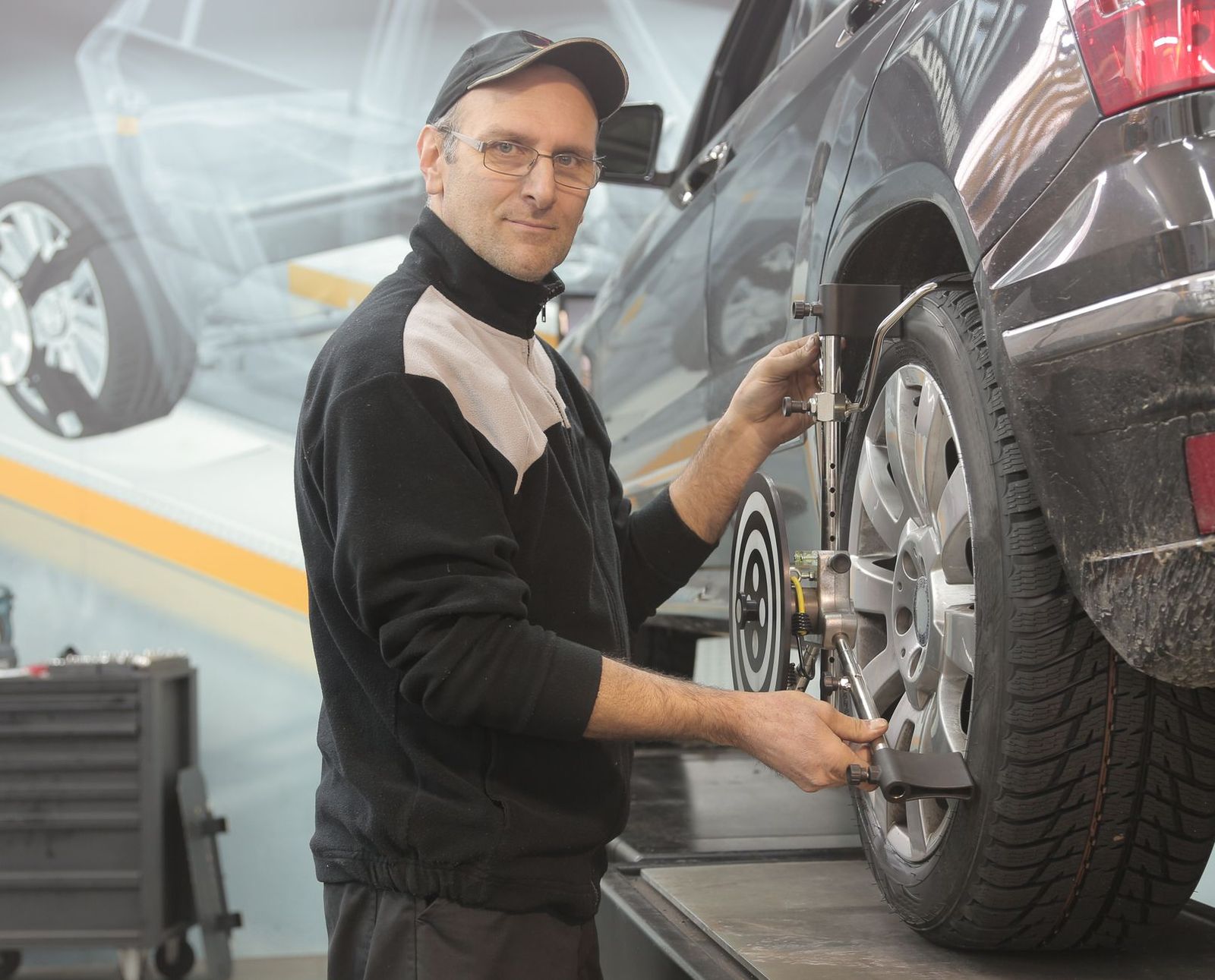 Technicien réalisant un alignement de roue avec équipement de géométrie